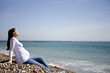 A pregnant woman sitting on the beach, relaxing