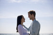 A pregnant woman and her partner embracing on the beach