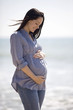 A pregnant woman standing on the beach, smiling