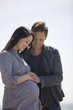 A pregnant woman and her partner standing on the beach