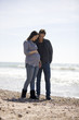 A pregnant woman and her partner standing on the beach