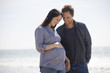 A pregnant woman and her partner standing on the beach