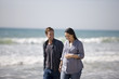 A pregnant woman and her partner walking on the beach