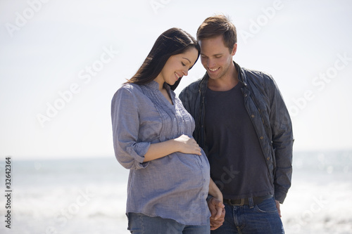 Photo: A pregnant woman and her partner standing on the beach A pregnant woman and her partner standing on the beach