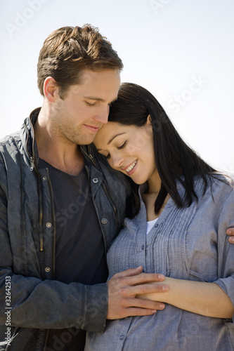 Photo: Portrait of a pregnant woman and her partner embracing Portrait of a pregnant woman and her partner embracing