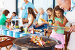 Girl and grandfather at the barbecue grill with family in backgr