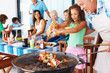 Grandfather and grand daughter barbecuing with family in the bac