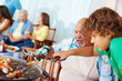 Grandfather and grandson barbecuing with family in the backgroun