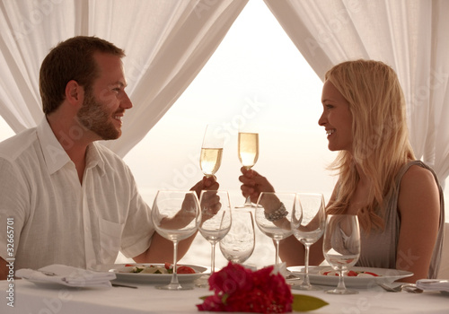 Photo: Smiling young couple having dinner in the beach Smiling young couple having dinner in the beach