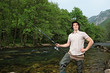Young fisherman posing while fishing on a river with trees in th Young fisherman posing while fishing on a river with trees in th