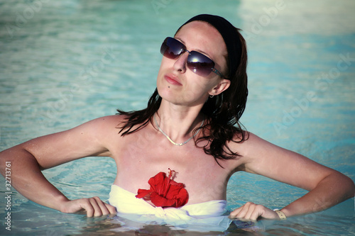 Foto: Young woman in the pool with a flower Young woman in the pool with a flower