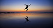 Silhouette of a jumping man on the beach by the ocean
