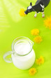 A cow and a milk jug against a bright green background