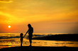 Pregnant mother and her child as silhouettes by the sea