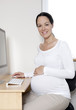 Photo: Pregnant woman smiling to camera at computer desk Pregnant woman smiling to camera at computer desk