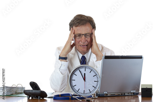 Foto: Gestresster Arzt mit Uhr vor sich hat Migräne wegen Zeitdruck Gestresster Arzt mit Uhr vor sich hat Migräne wegen Zeitdruck