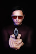 criminal pointing a gun in sunglasses in the dark