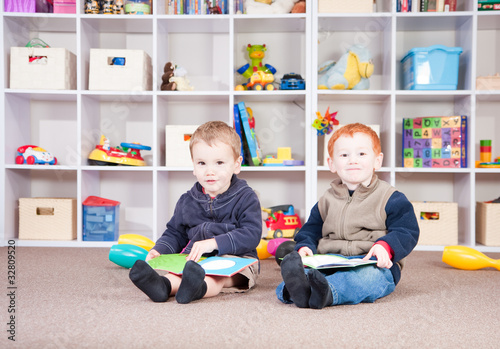 Photo: Smiling children reading kids books in play room Smiling children reading kids books in play room