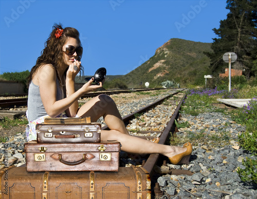 Photo: Young traveling woman with her suitcases on the railway tracks Young traveling woman with her suitcases on the railway tracks