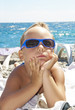 The boy in a sun glasses sunbathes on a beach