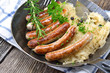 Schweinswürstl mit Kraut in der Pfanne serviert