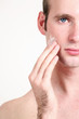 Foto: Close-up portrait of young handsome man applying face cream Close-up portrait of young handsome man applying face cream