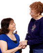 An older woman greeting a younger woman with a hand shake