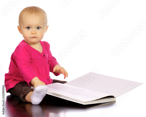 Photo: Infant baby girl enjoying and discovering books Infant baby girl enjoying and discovering books