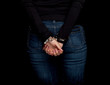 standing back woman with handcuffed hands, black background .