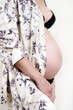 Portrait of a pregnant woman touching her belly with hands