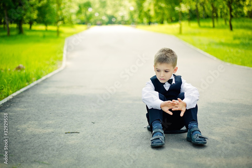 Photo: boy sitting down in a park boy sitting down in a park