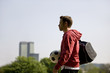 A young man in the park, carrying a football and a sports bag