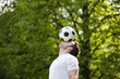 A young man balancing a football on his forehead