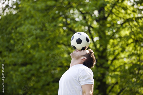 Photo: A young man balancing a football on his forehead A young man balancing a football on his forehead