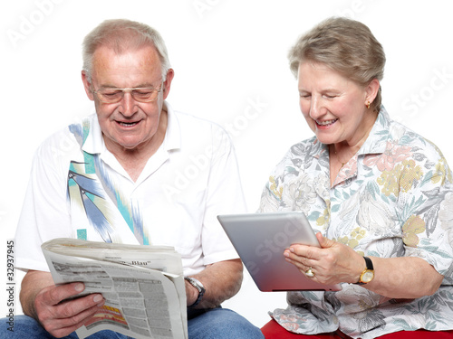 Foto: Seniors reading and having fun with touchpad and newspaper Seniors reading and having fun with touchpad and newspaper