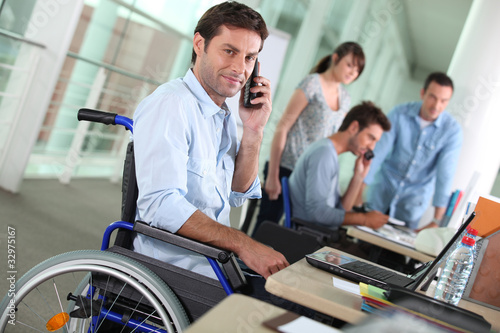 Photo: Man in wheelchair with mobile phone at work Man in wheelchair with mobile phone at work