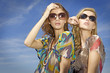 two beautiful girl in sunglasses on background blue sky