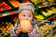 Kleiner Junge isst Brötchen im Supermarkt