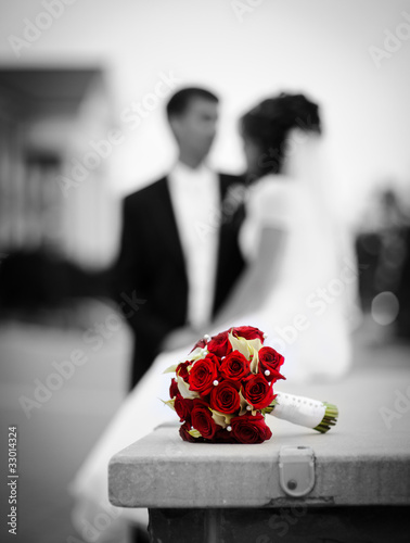 Photo: Wedding bouquet with bride and groom on the background Wedding bouquet with bride and groom on the background