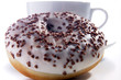 Donut mit Schokostückchen garniert vor weißer Tasse