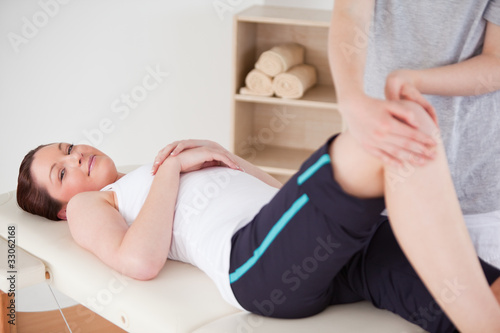 Photo: Masseuse massing the knee of a beautiful woman looking a the cam Masseuse massing the knee of a beautiful woman looking a the cam