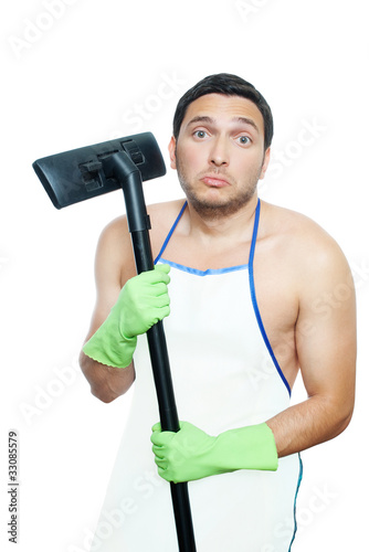 Photo: Sad young man in apron holding vacuum cleaner brush Sad young man in apron holding vacuum cleaner brush