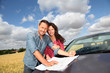 Couple looking at road map on car hood