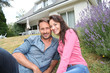 Portrait of happy couple sitting in front of their new house