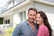Happy couple standing in front of new home