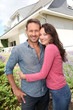 Happy couple standing in front of new home