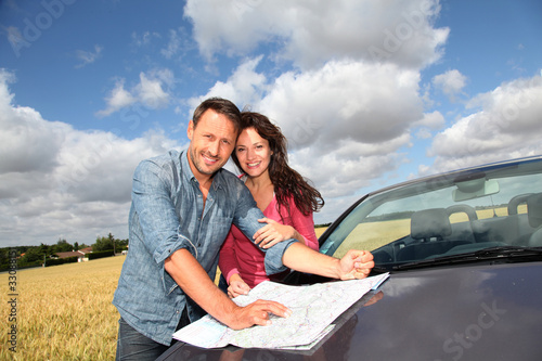 Foto: Couple looking at road map on car hood Couple looking at road map on car hood