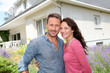 Happy couple standing in front of new home