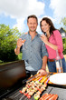 Happy couple cooking meat on barbecue grill