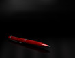 Red ball point pen over a black background